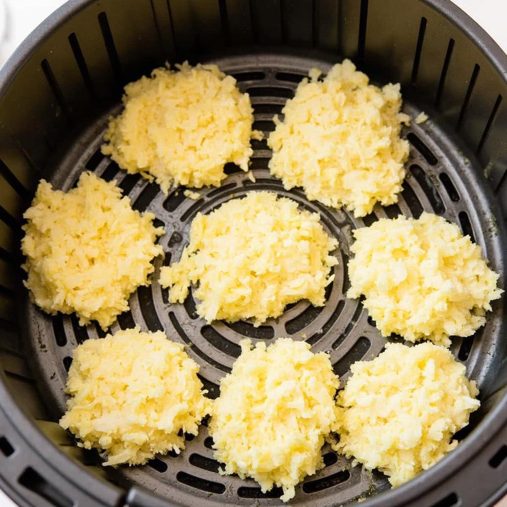 Frozen hash browns in air fryer basket ready to cook